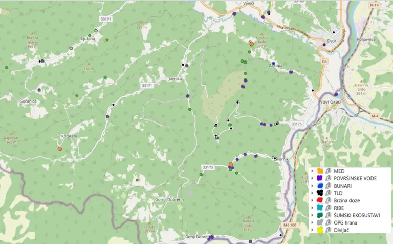 Detaljna karta prikazuje šumovito područje s različitim oznakama koje označavaju različite vrste podatkovnih točaka kao što su površinske vode, bunari i izvori hrane. Određeni markeri kodirani su bojama i označeni kategorijama kao što su MED, TLQ itd. Ceste i gradovi prikazani su na periferiji.